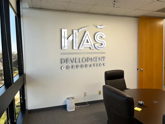 HASDC Development Corporation chrome logo on a meeting-room wall