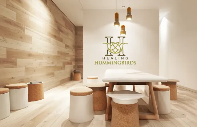 Healing Hummingbirds logo on a wood-paneled wall in a bright room